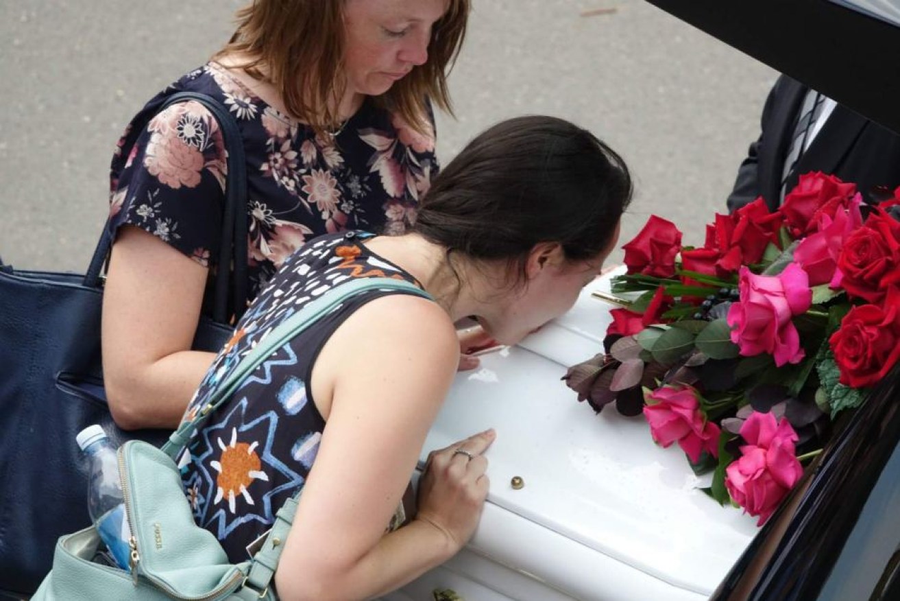 A mourner kisses Jessica Falkholt's coffin outside the church.