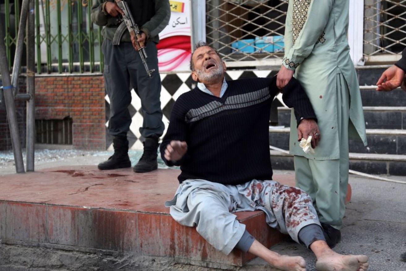 Splattered with blood, a survivor of the attack collapses with shock and grief in central Kabul.