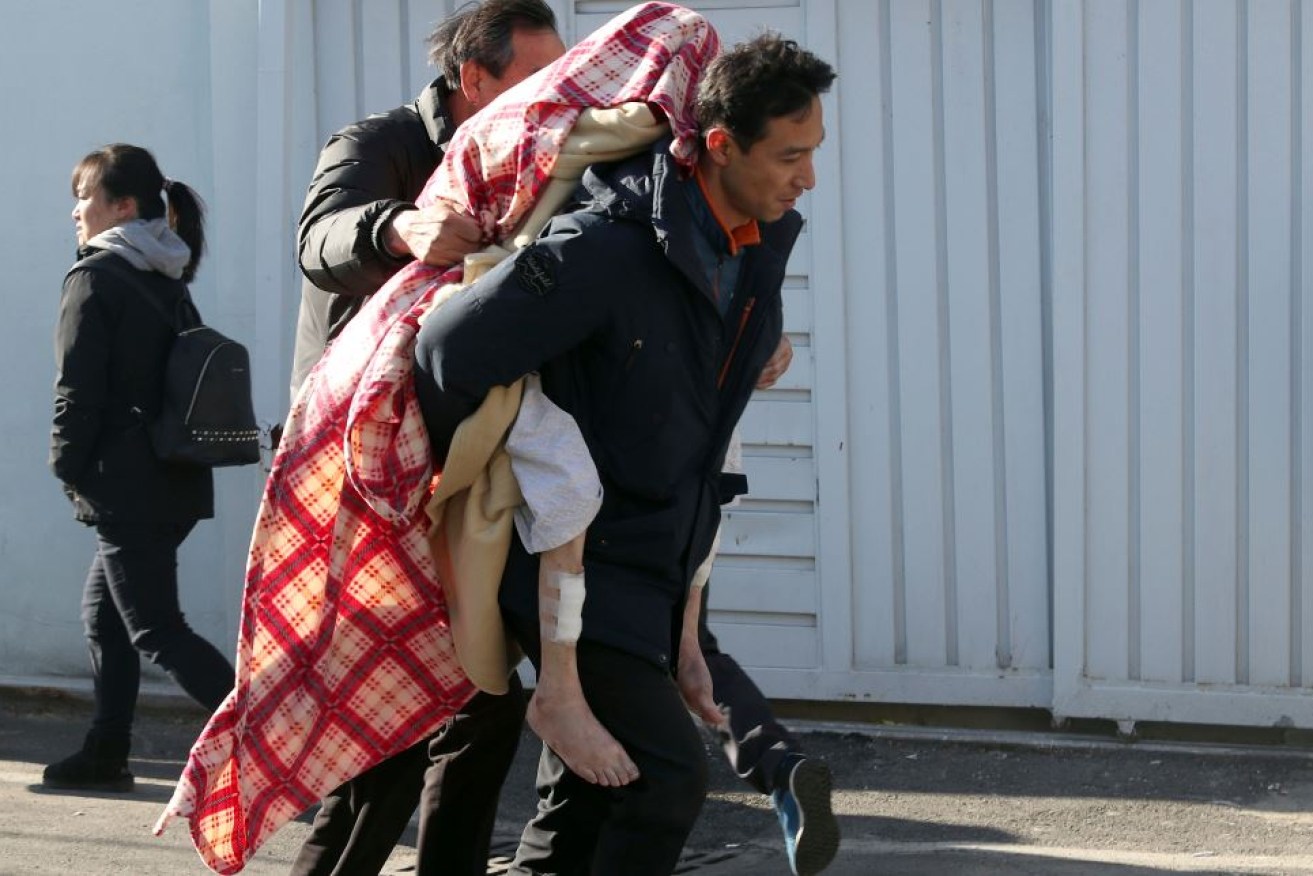 Draped in a blanket against the winter chill, a patient is carried from the burning hospital.