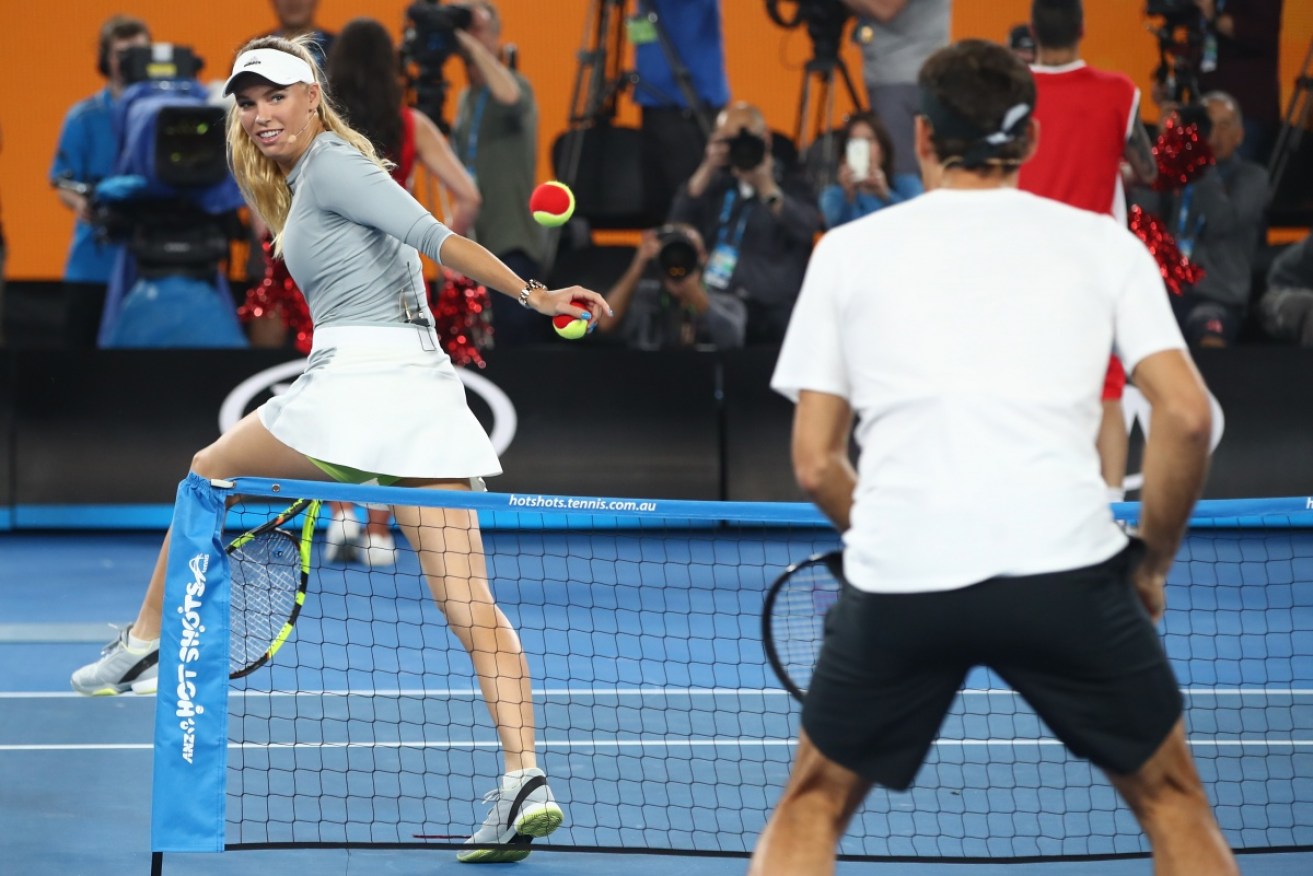 Fun and games: Caroline Wozniacki hits a trick shot to Roger Federer.