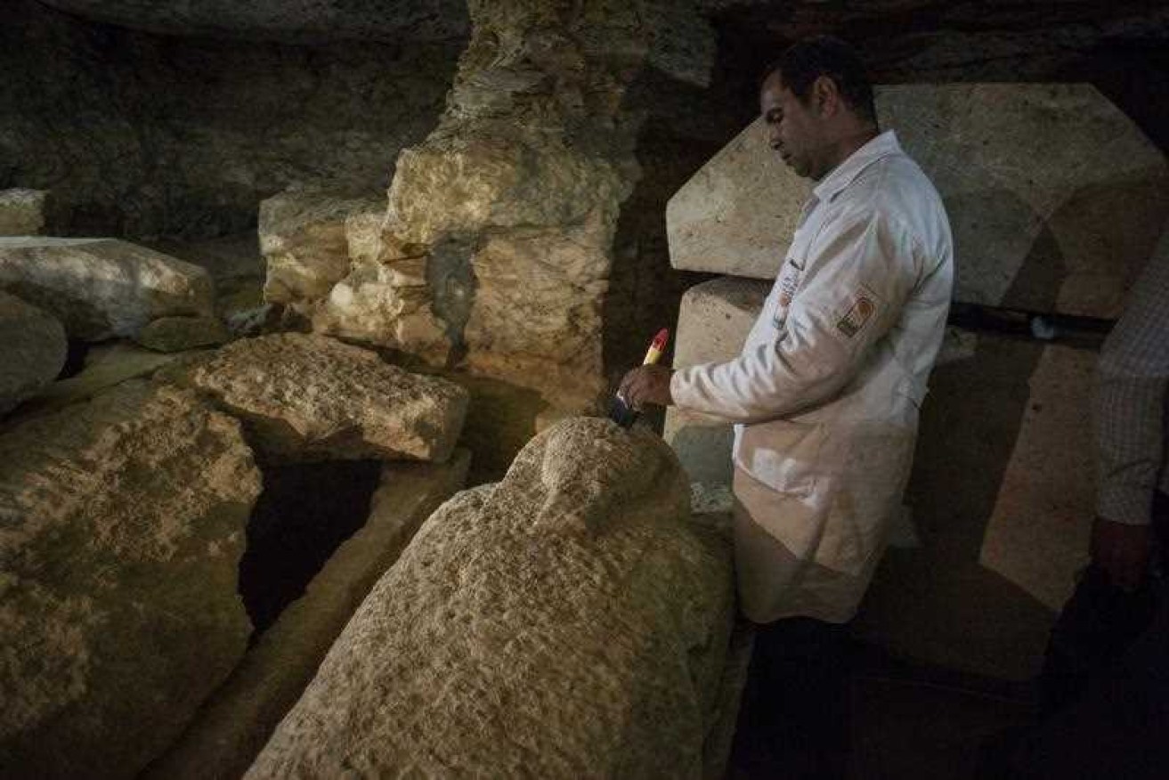 An Egyptian archaeologist works on a sarcophagus at the site of an ancient Egyptian cemetery.