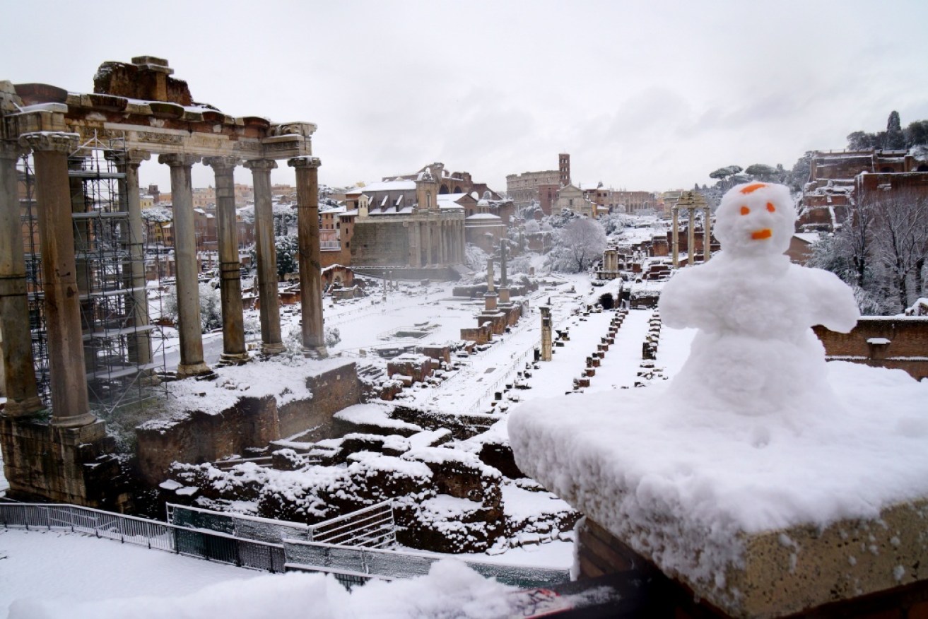 The Roman forum is blanketed with snow.
