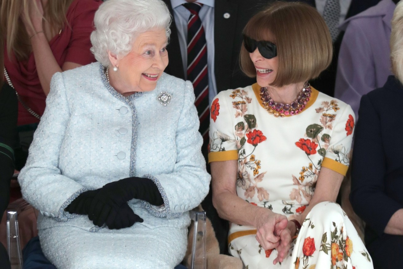 Queen Elizabeth II sits next to Anna Wintour as they view Richard Quinn's runway show.