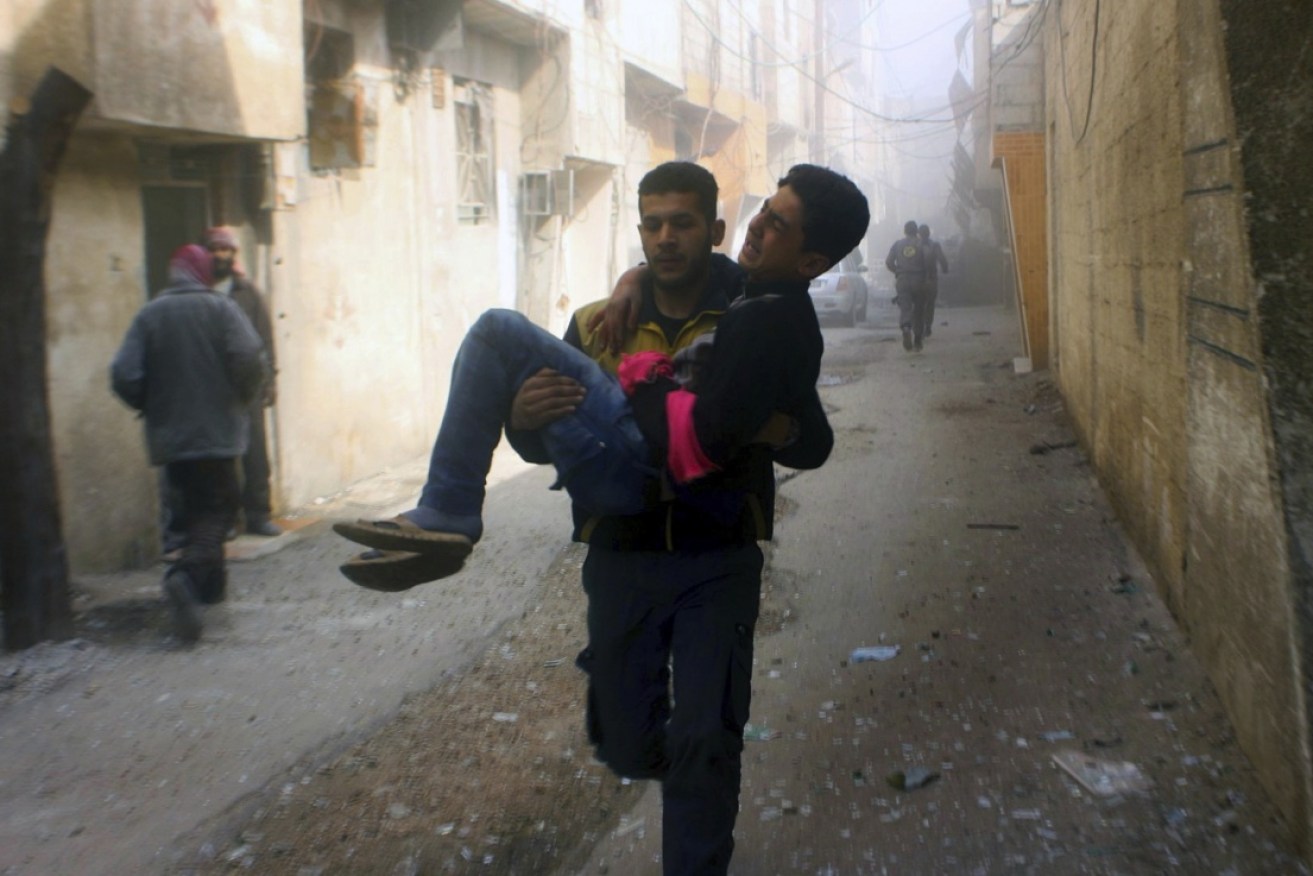 A member of Syria's White Helmets carries a young victim of the bombing. 