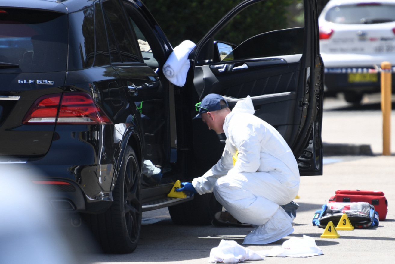 A police forensics expert picks through Mahmoud "mich" Mawi's bullet-riddled SUV.