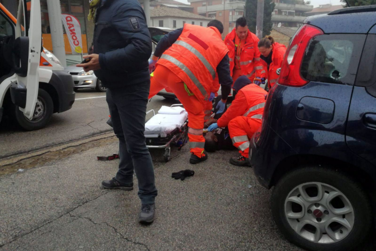 Paramedics tend to one of the six wounded Africans shot at random in the Italian city of Macerata.