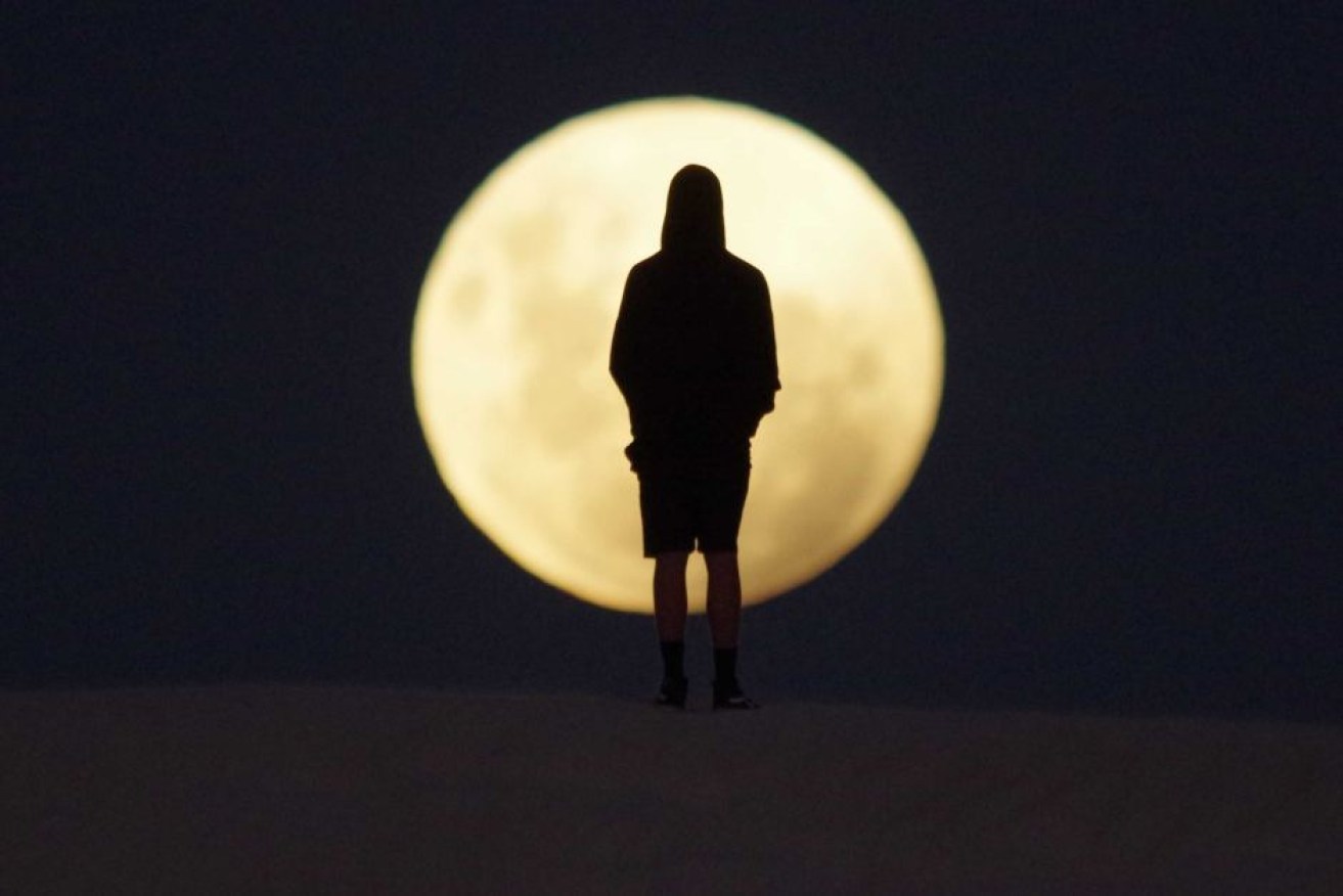 A man is silhouetted by the moon in sand dunes in Lancelin, north of Perth.