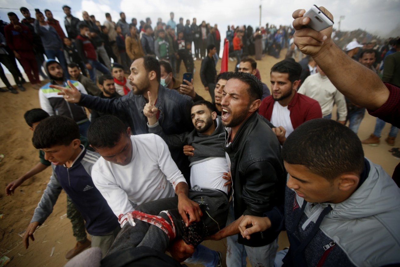 Protestors evacuate a wounded youth after clashes with Israeli forces.