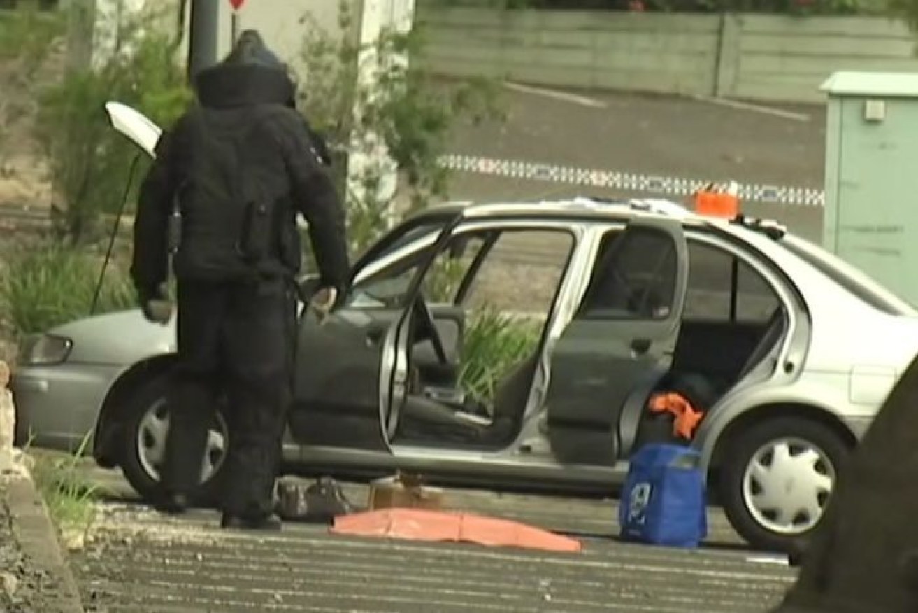 A member of the bomb squad examines an explosive device found in a car at Redbank Plaza shopping centre. 