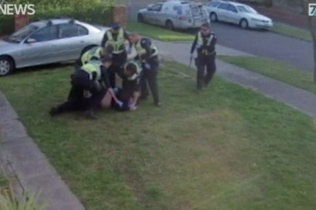 Footage shows John being dragged from his front door, pinned to the ground, sprayed with capsicum spray and hosed down.