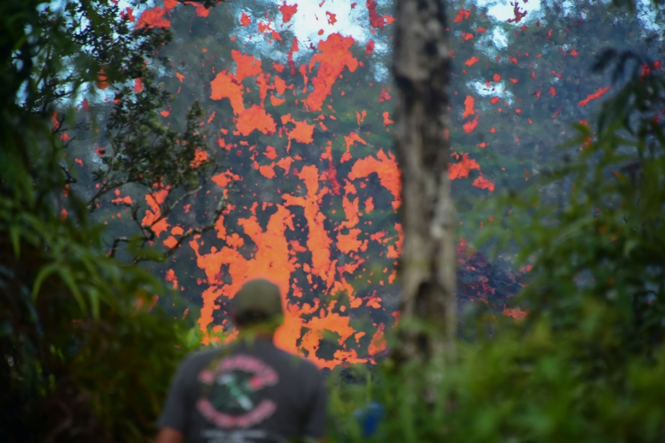 A man watches as lava is seen spewing from a fissure in the Leilani Estates subdivision near the town of Pahoa. 