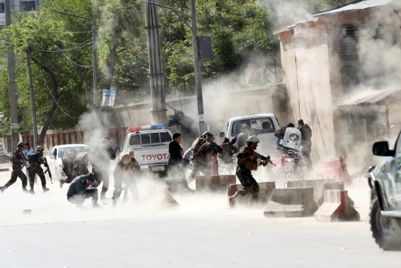 Afghan police dash through the smoke of a Taliban attack in Kabul, part of a wave of assaults erupting across half the country.