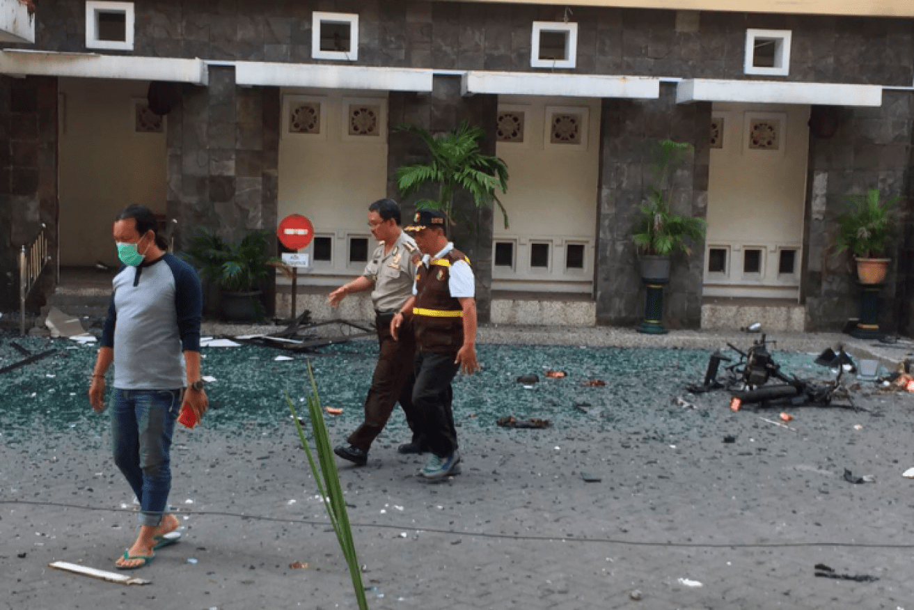 Police officers pick their way through the shattered glass and tangled wreckage at one of the Surabaya churches.