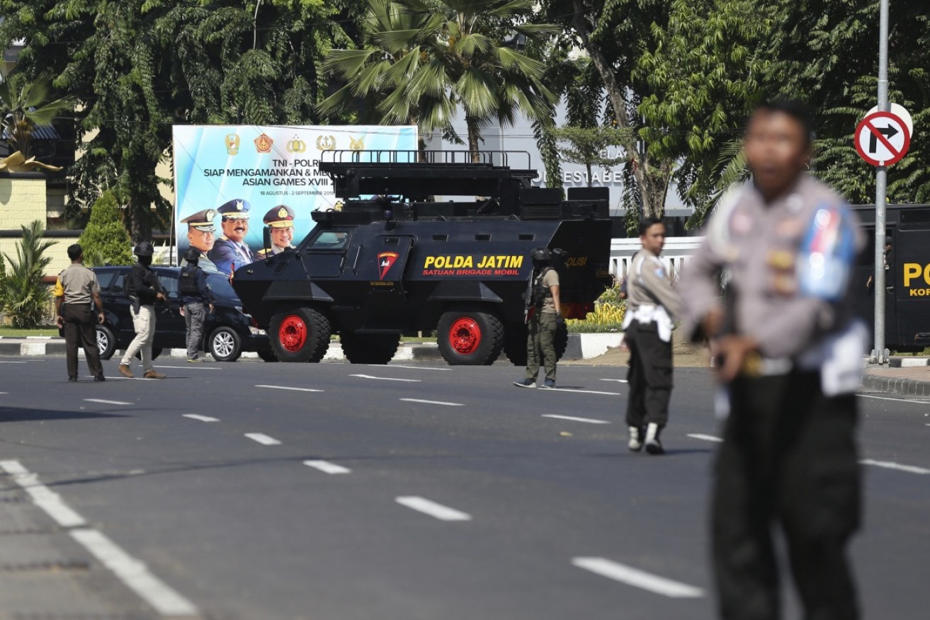 Officers block a road after this morning's car bombing at Surabaya's police headquarters.