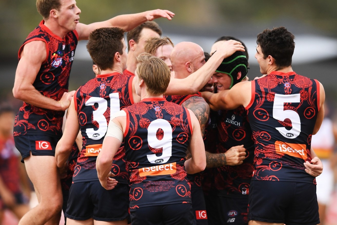Angus Brayshaw is congratulated by team mates after kicking a goal on the siren in Melbourne's 91-point win.