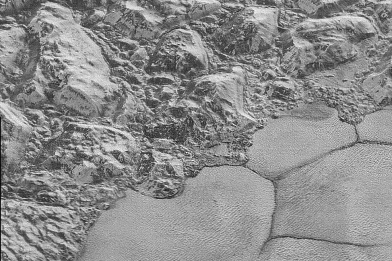 A mountain range on Pluto's Sputnik Planitia ice plain, with dunes in the bottom half of the picture.