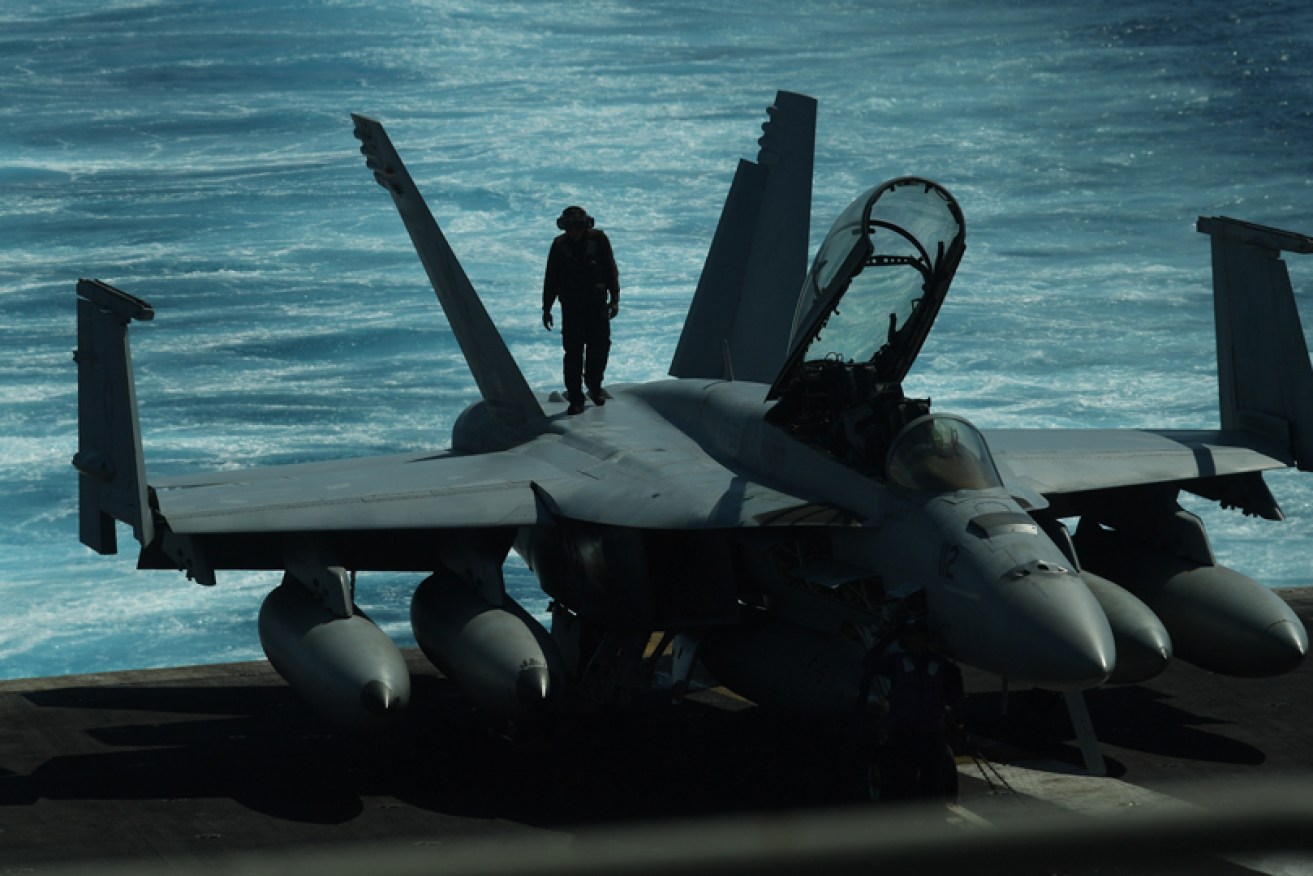 A sailor inspects an FA-18 fighter jet aboard a US aircraft carrier in the South China Sea.