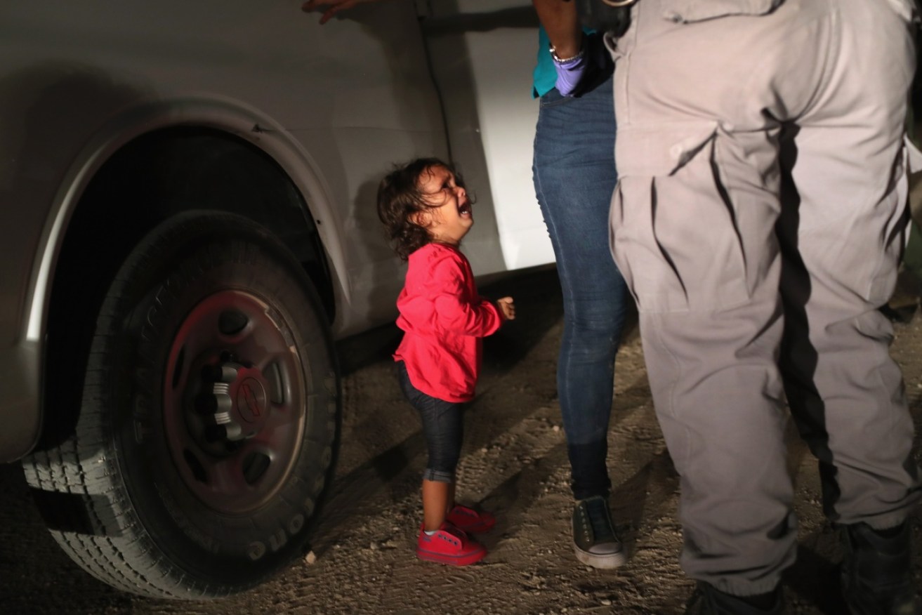 A two-year-old Honduran asylum seeker cries as her mother is searched and detained near the U.S.-Mexico border on June 12, 2018.