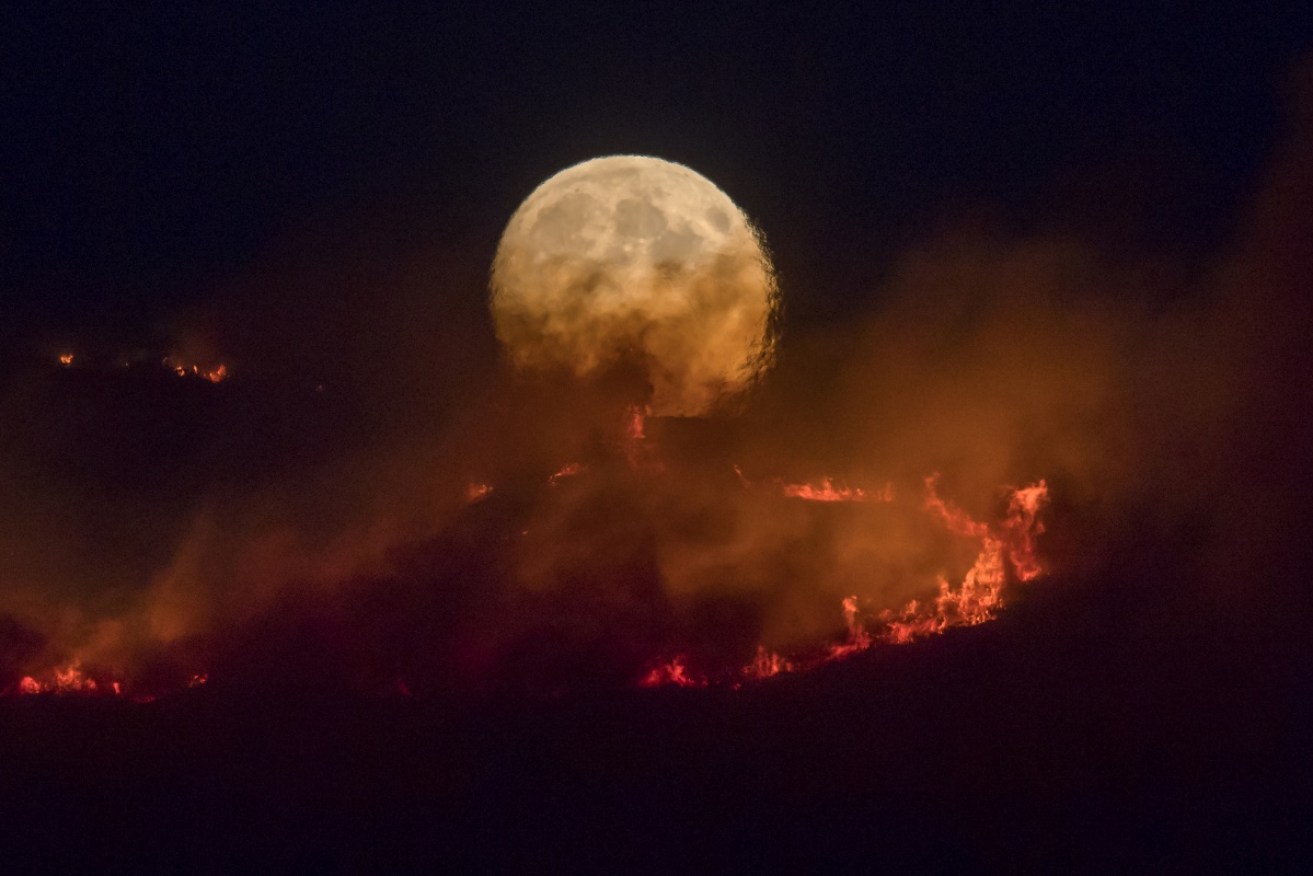 The full moon rises behind the burning Saddleworth Moor near Manchester. The out-of-control fire has been burning for several days.