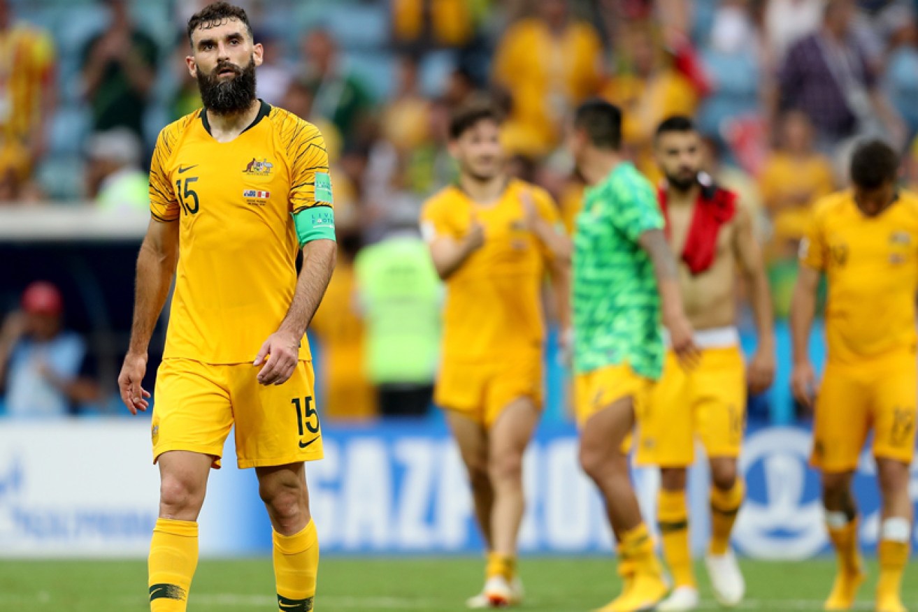 A dejected Mile Jedinak leads the Socceroos off after their loss to Peru in Sochi on June 26.