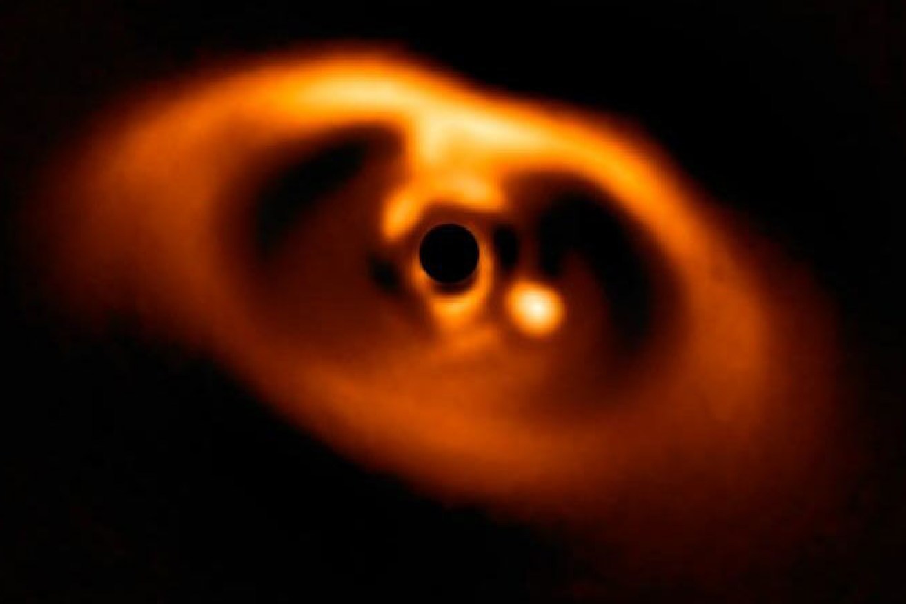 The baby planet is seen as the bright spot to the right of the black dot, its host star.
