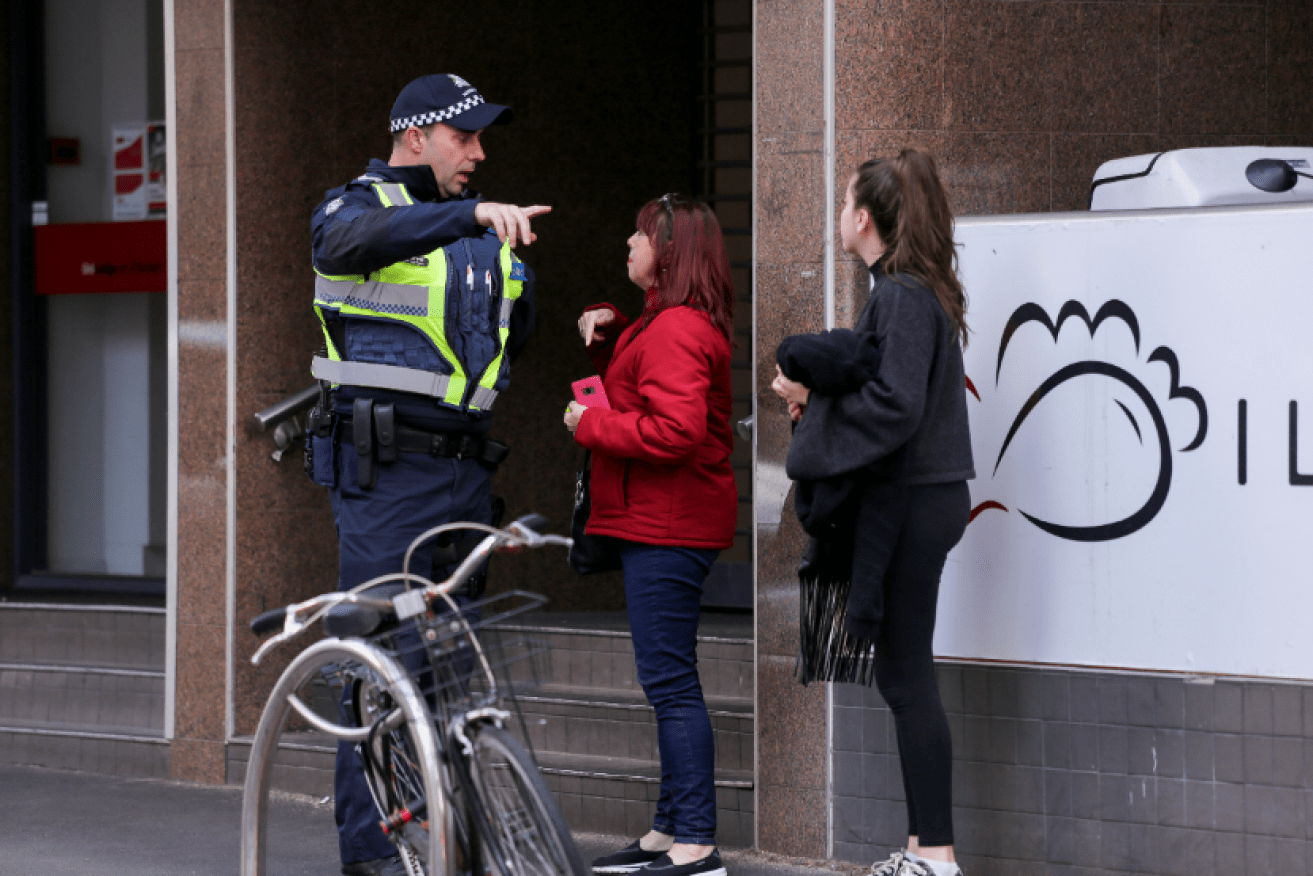 A police officer directs passersby away from the high-rise tower where the woman died despite paramedics' bid to save her.