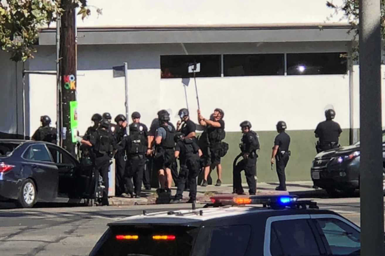 SWAT officers shelter at the rear of the supermarket as the hostage drama intensifies.