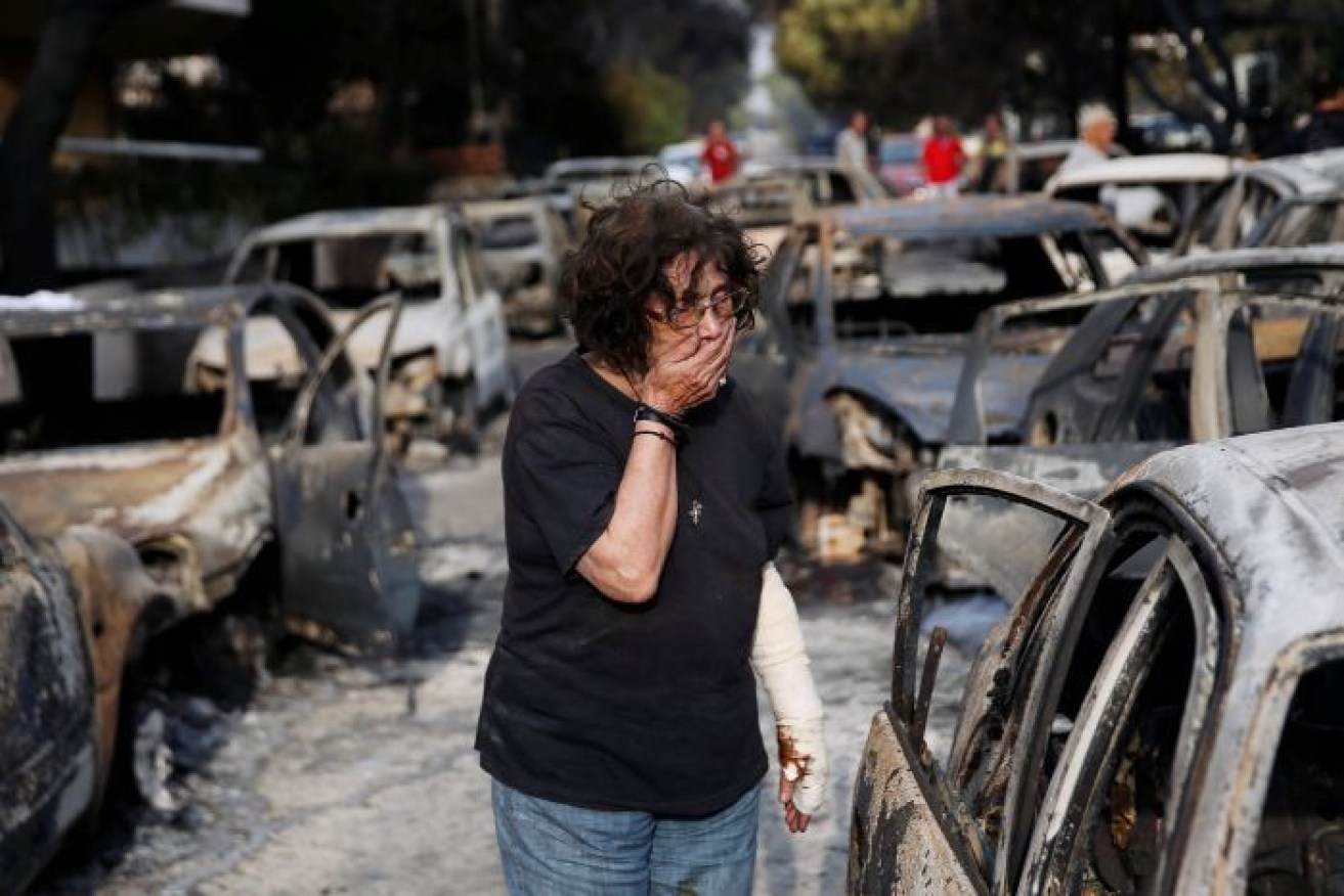 A Greek woman searches for her dog among burnt out cars. 