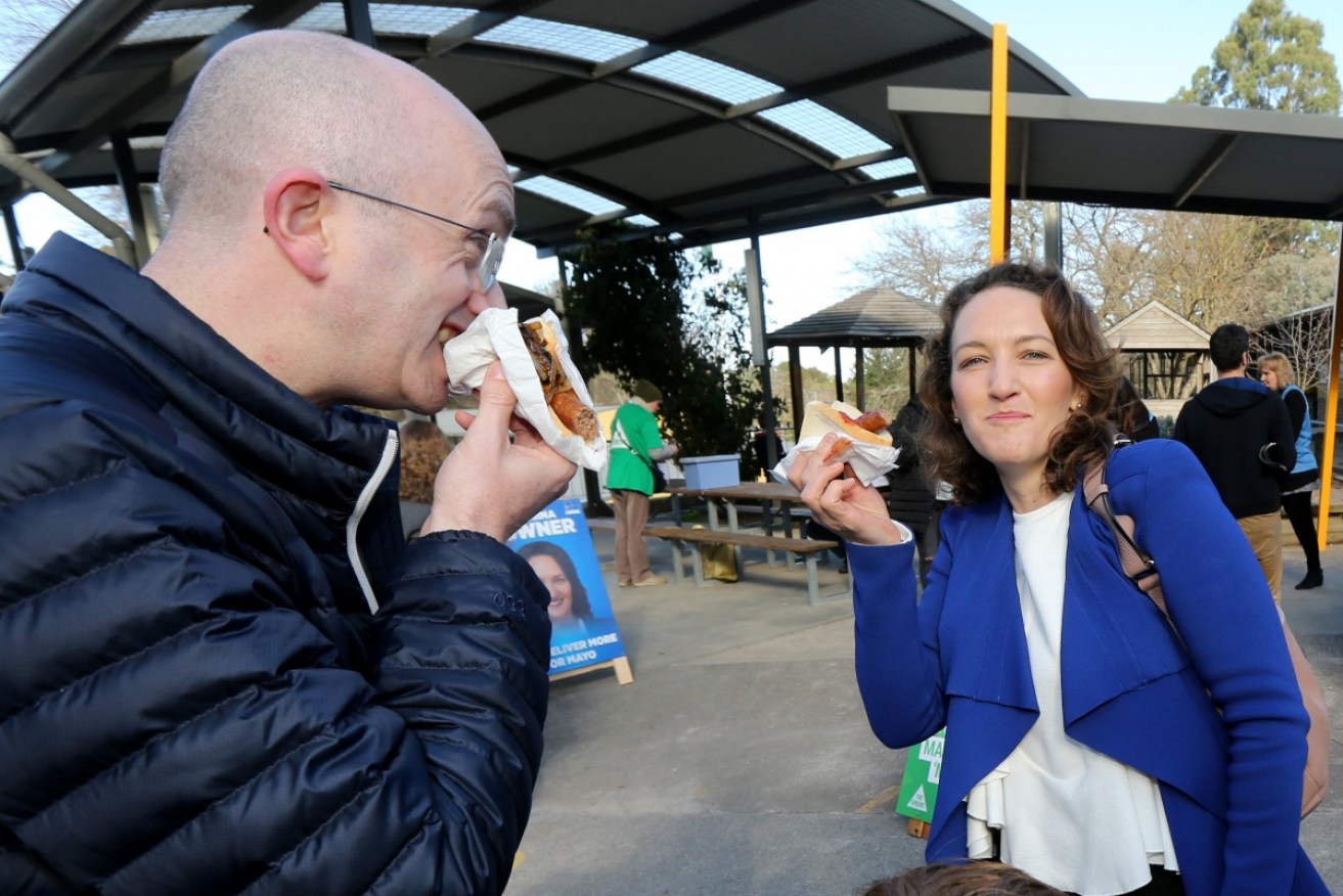 The Liberals' Georgina Downer casts her vote in SA and enjoys a democracy sausage as she waits out the count against Centre Alliance's Rebeckha Sharkie.