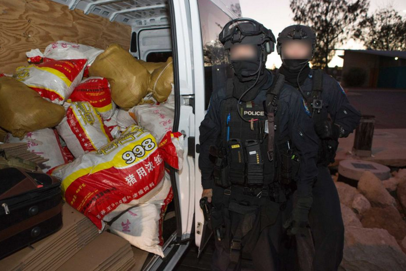 Australian Federal Police, faces obscured to protect their identities, guard a van loaded with a tonne of Myanmar-made ice.