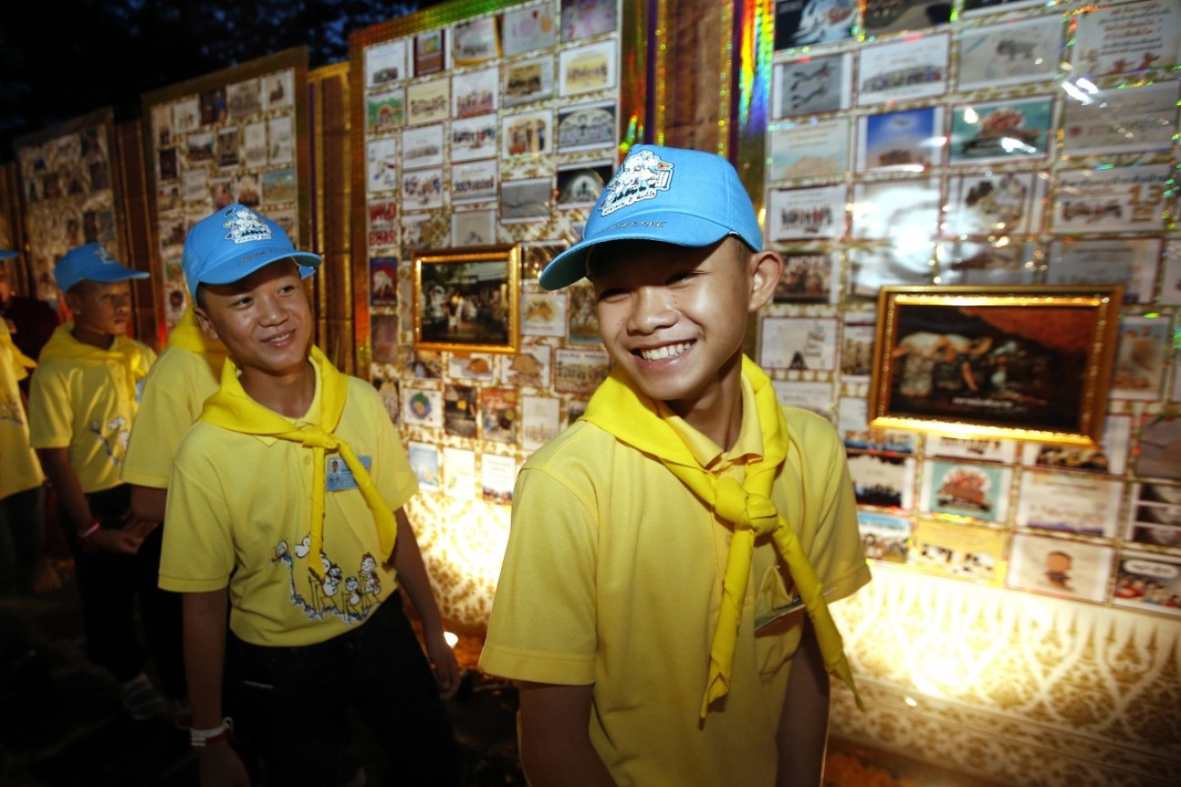 Boys from the Wild Boars soccer team tour a photo exhibition of volunteers that helped them. 
