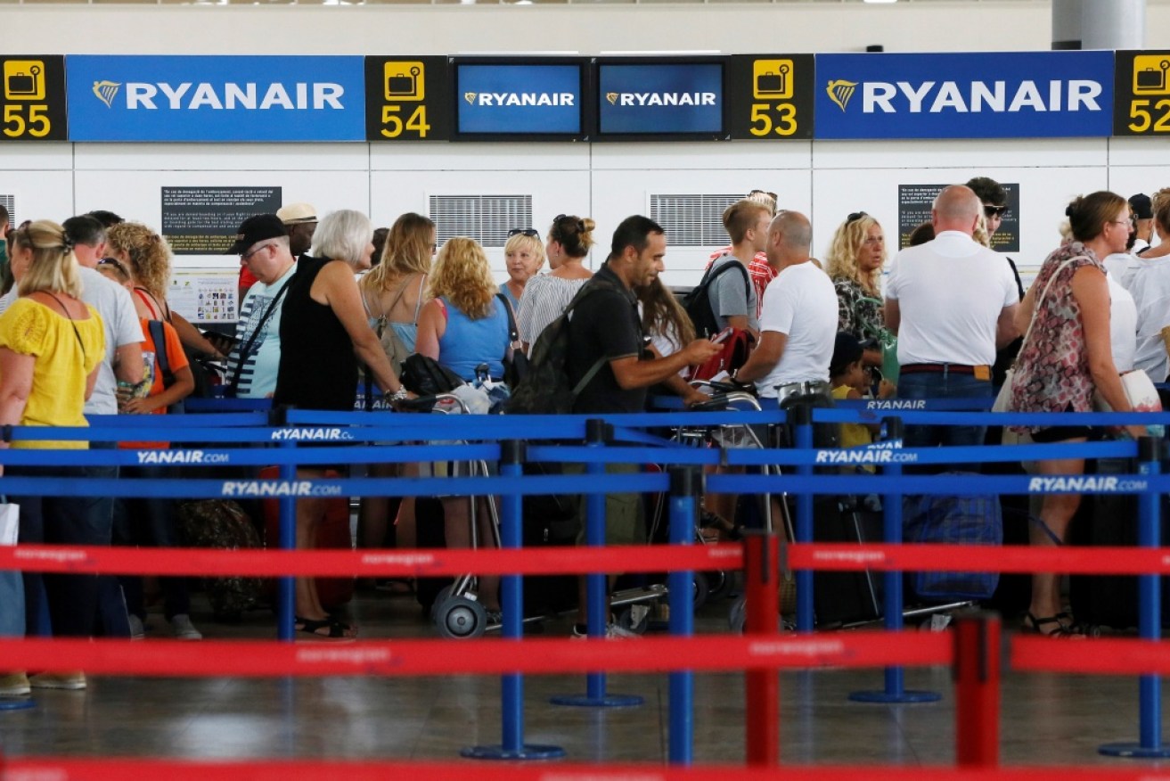 Passengers wait at Ryanair's check-in desks at Alicante airport in Spain.