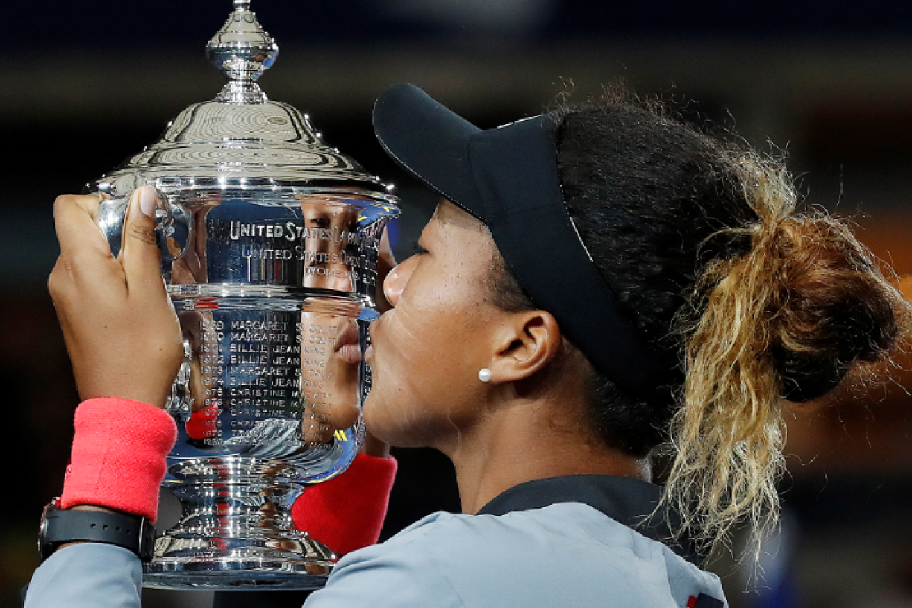 Japan's Naomi Osaka kisses a trophy that will be forever tarnished by memories of her opponent's tempestuous tantrum.