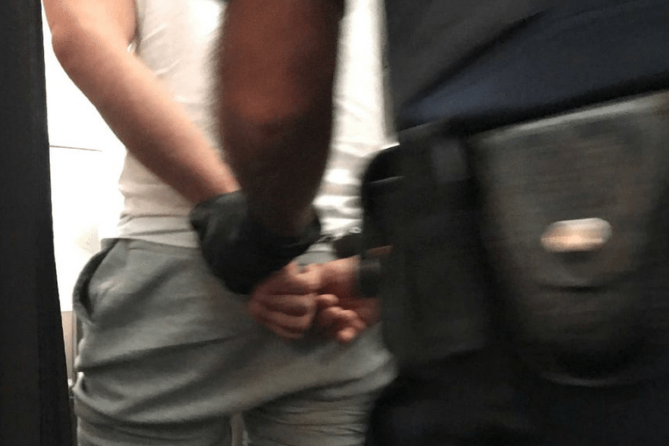 Hands handcuffed behind his back, the 'agitated' passenger is taken into custody.