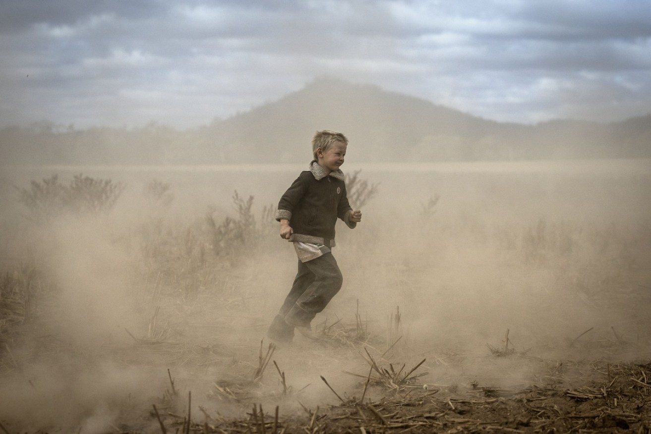 Harry Taylor, 6, plays on the dust bowl his family farm has become. Rising emissions promise more drought.