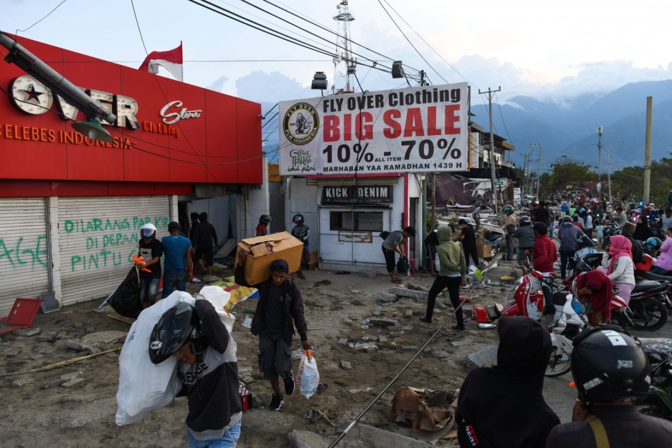 Survivors loot a clothing store in Palu for basic supplies on October 1.