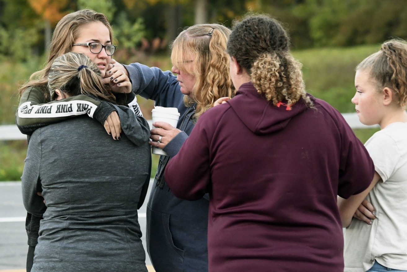 Friends of victims who died in Saturday's fatal limousine crash comfort each other after placing flowers at the intersection where the accident happened. 