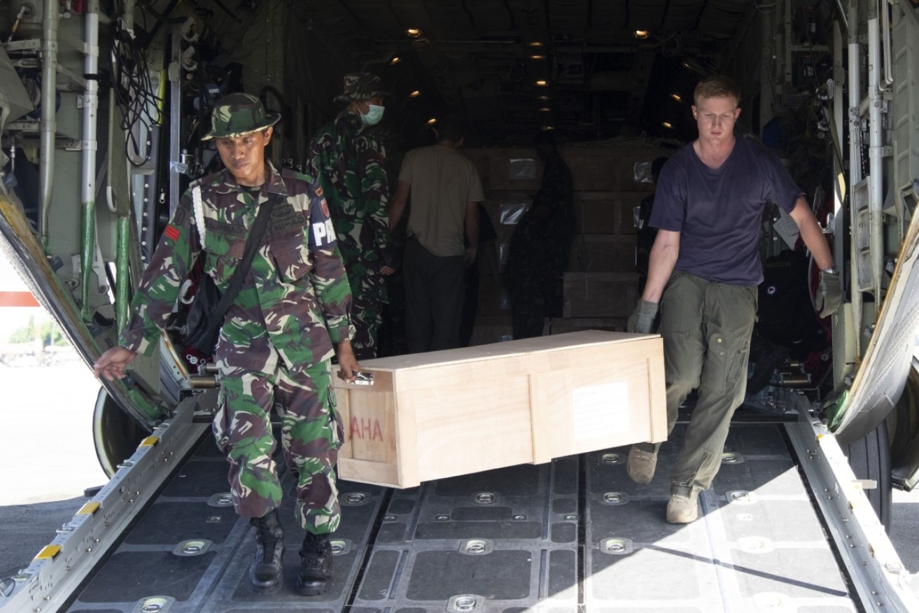 An Indonesian soldier helps a New Zealand aid worker offload supplies at Palu on Monday. 
