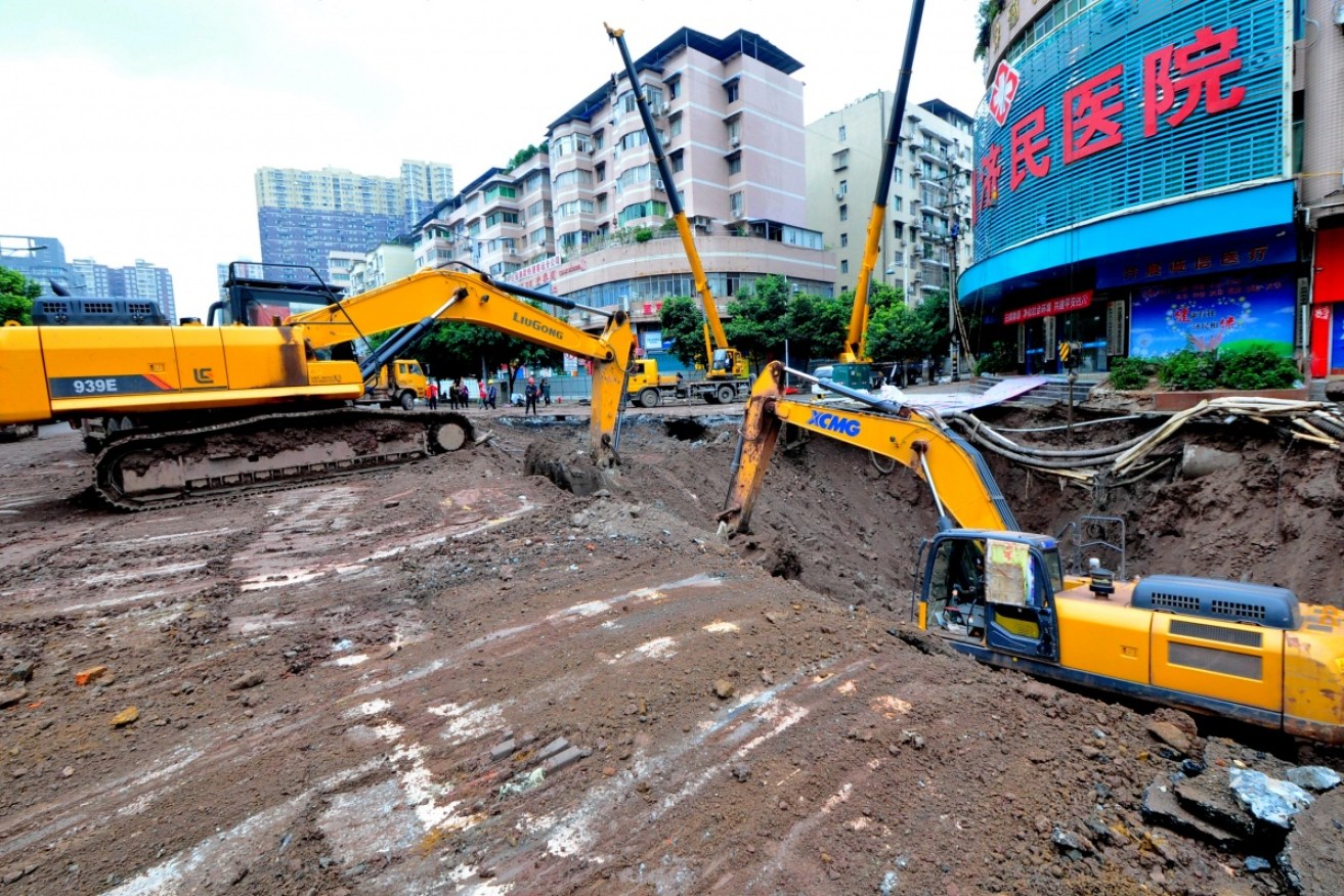 Rescue workers use excavators to search for missing people after a pavement collapsed on Sunday afternoon in Dazhou. 