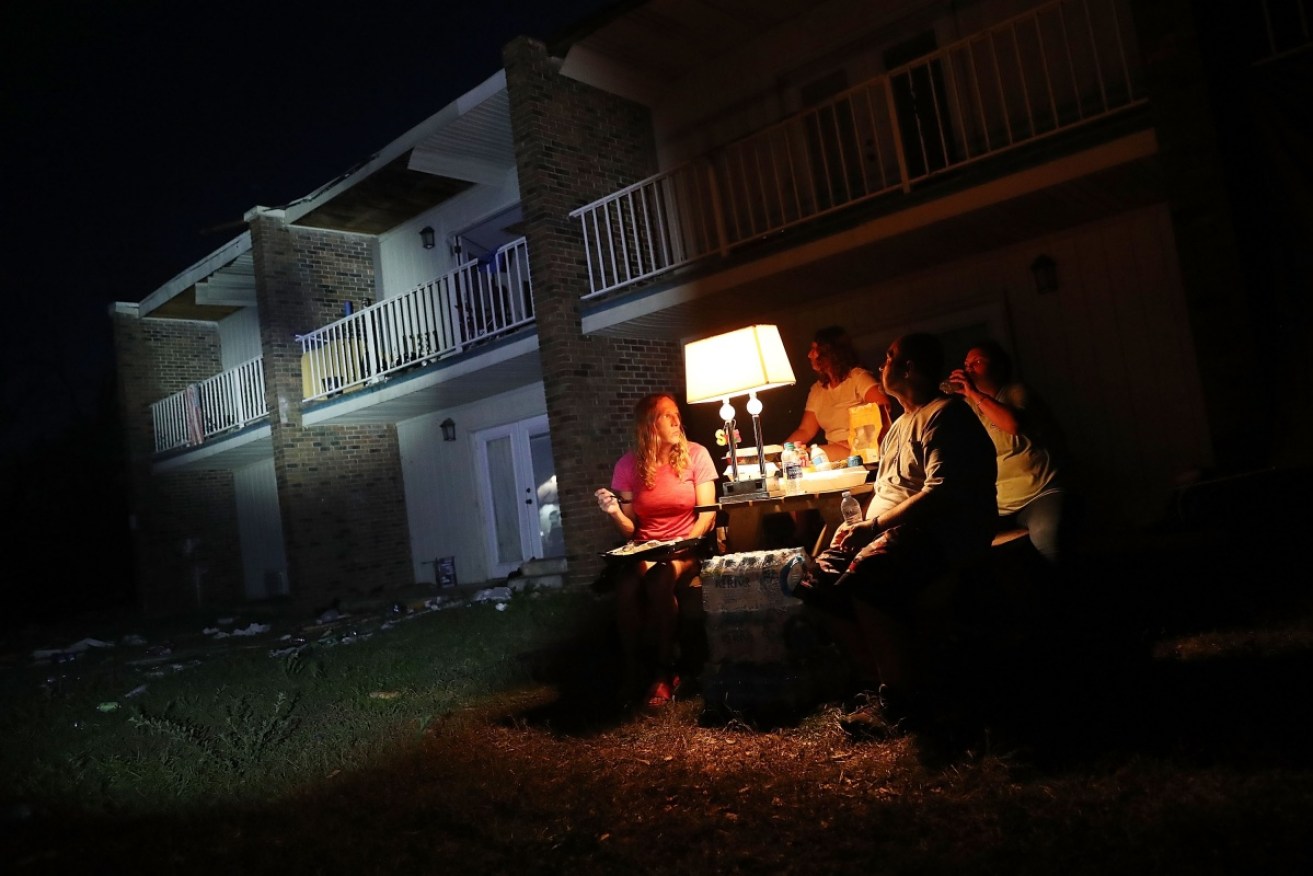 Panama City residents use a generator to power a lamp as they sit outside their apartment that doesn't have power after being damaged by Hurricane Michael on October 15.