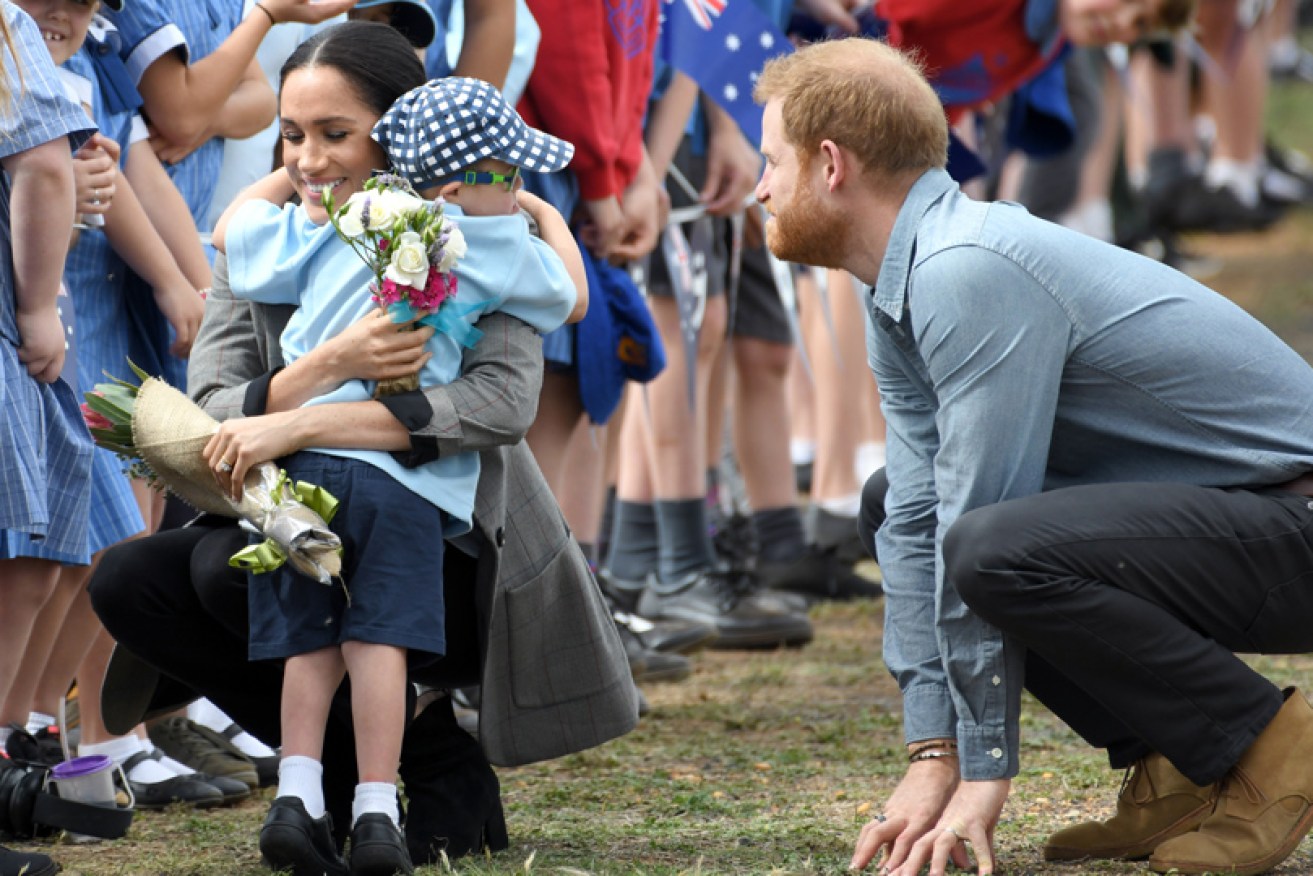 Schoolboy Luke Vincent, 5, hugs the Duchess of Sussex in Dubbo on October 17 as Prince Harry is amused.