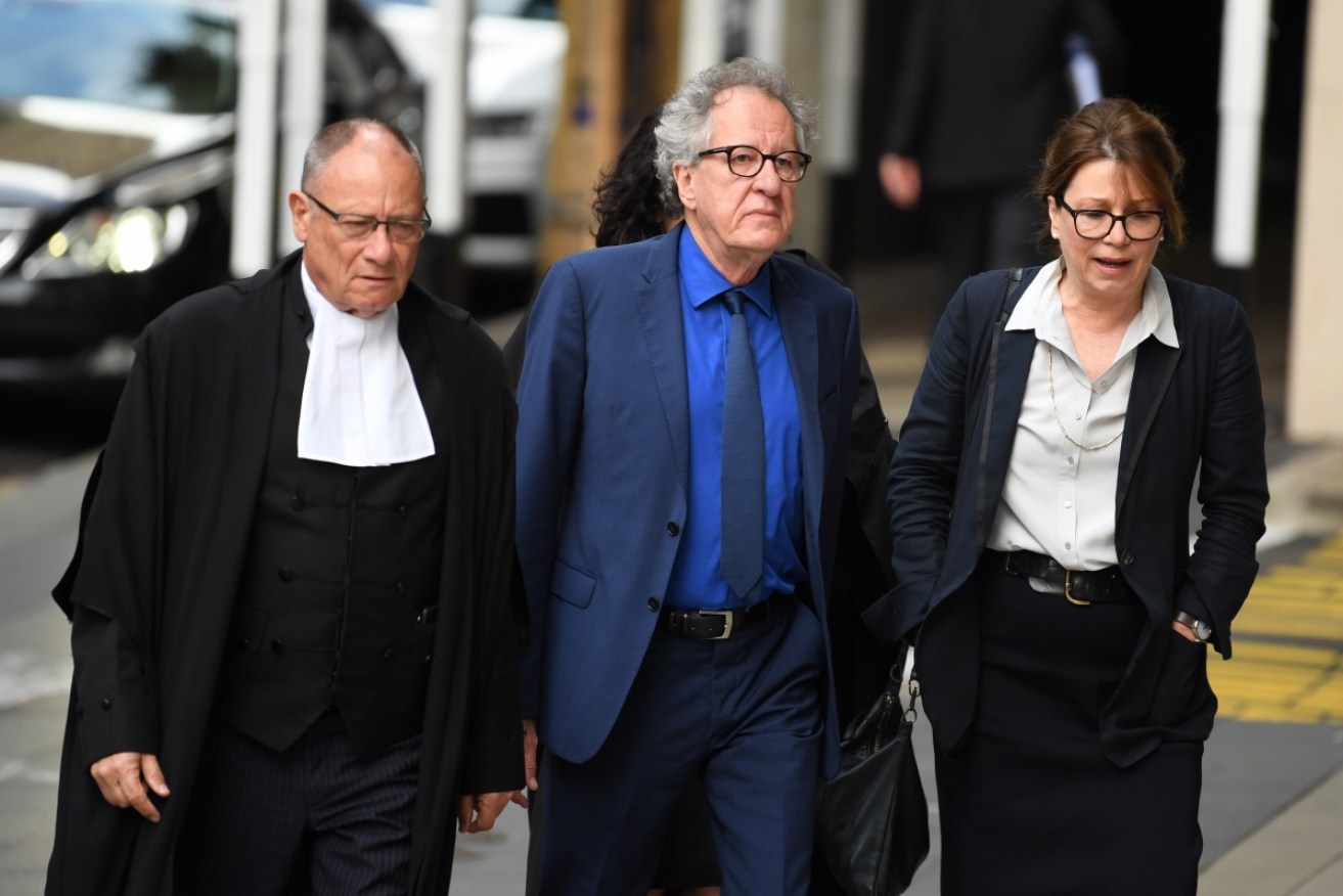 Geoffrey Rush arrives at court with his legal team. 