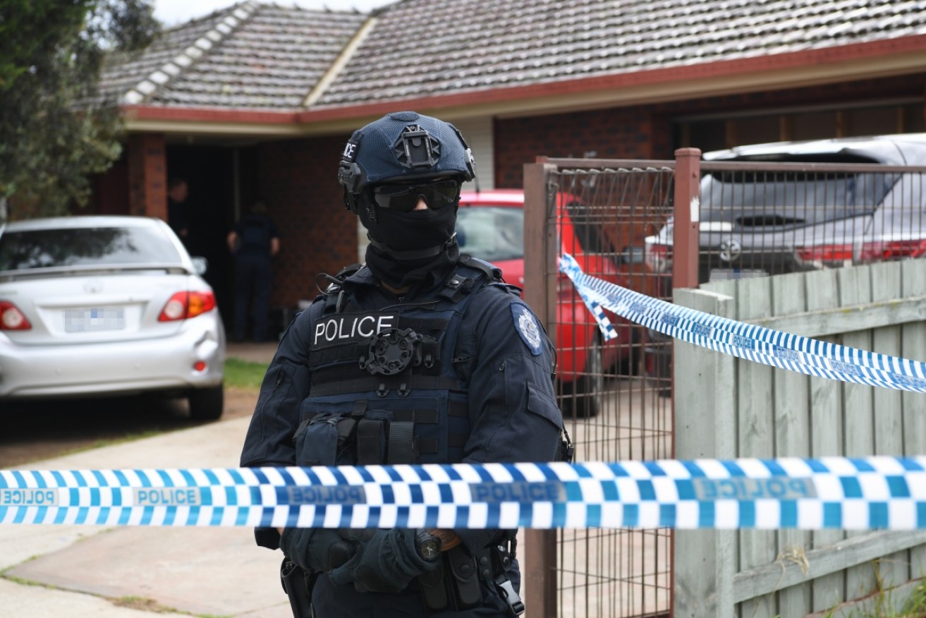 Police guard a property in Werribee in Melbourne's western suburbs after raids across Melbourne on Saturday.
