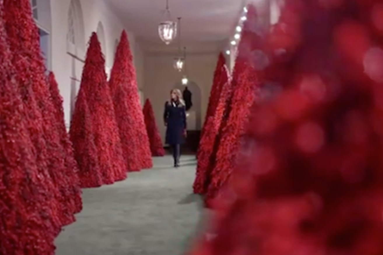 Melania Trump stalks her controversial corridors of red trees at the White House on November 26.