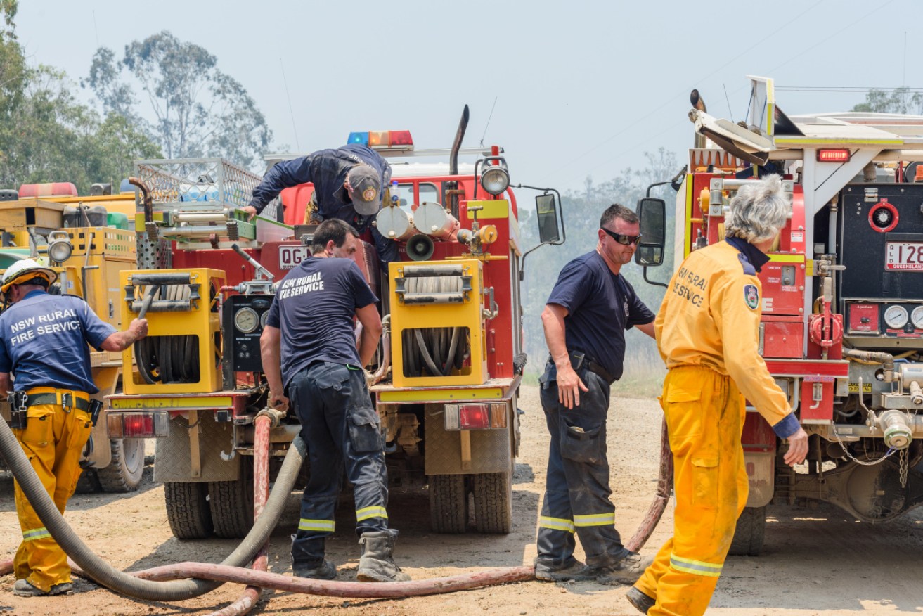 Captain Creek and Queanbeyan City rural fire fighters refill their trucks on Sunday.