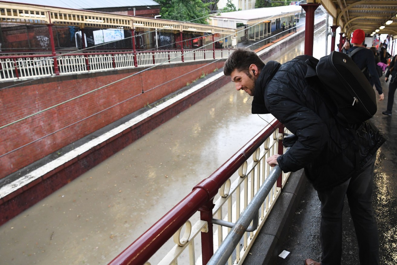 A lone commuter inspects the flooded railway tracks at South Yarra railway station on Friday afternoon.