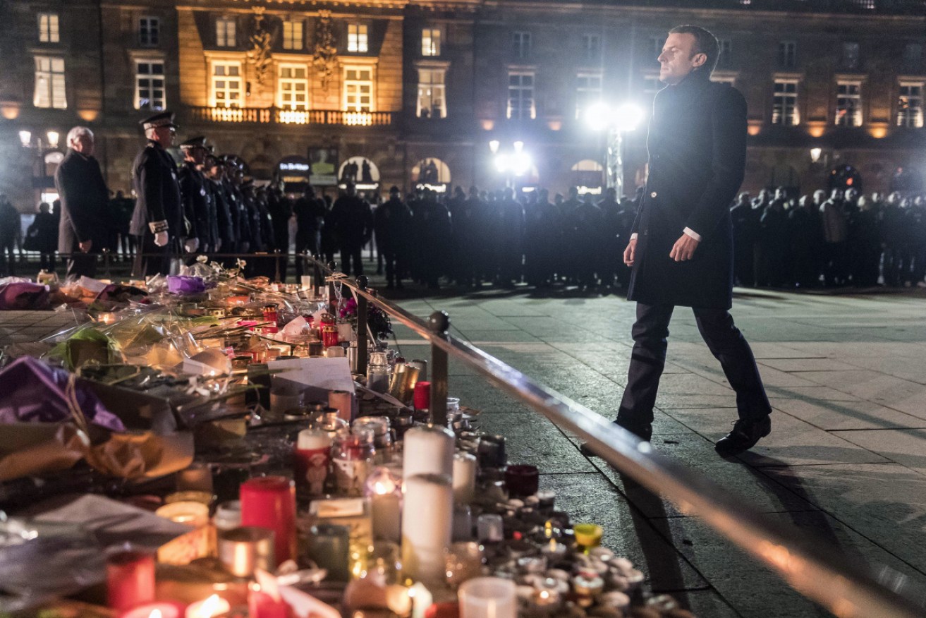 French President Emmanuel Macron pays tribute at a makeshift memorial to the victims of the Christmas market shooting.