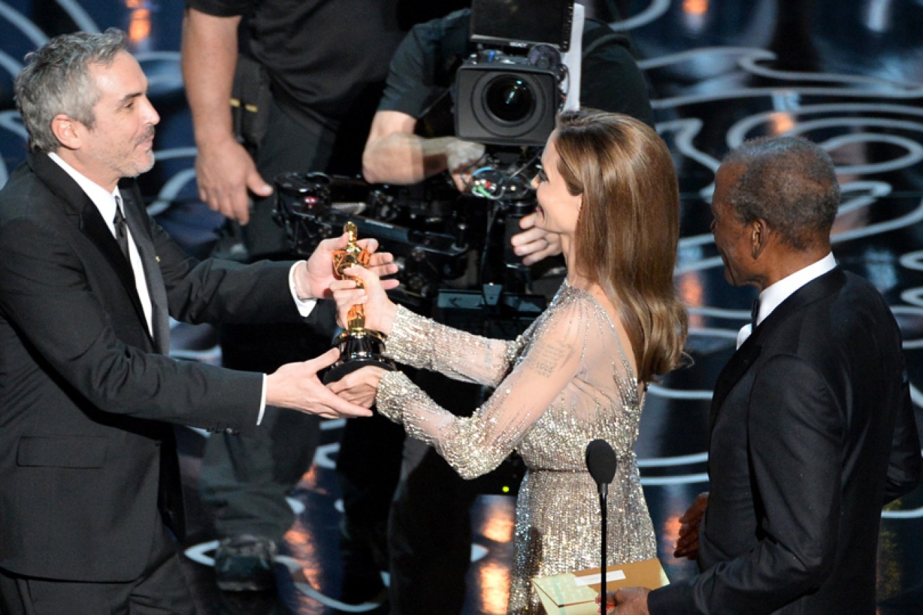 Alfonso Cuaron (who also won best editing) accepts the best director Oscar for <i>Gravity</i> from Angelina Jolie at the 2014 Academy Awards. 