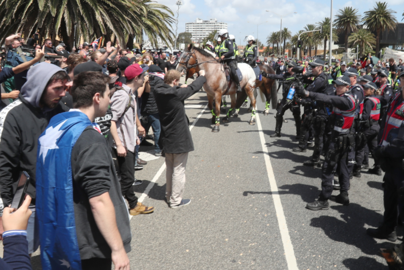 A thin blue line of police keep the demonstrators apart in St Kilda.