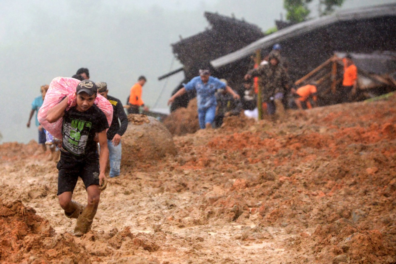 Residents evacuate their homes on January 1 as rescue workers search for survivors at the site of a landslide triggered by heavy rain in Sukabumi, West Java province.  